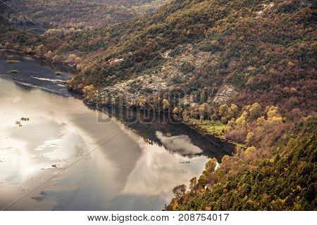 Autumn landscape with calm river and hills covered with gold colored trees in sunny autumn day with in Europe country Montenegro in autumn season