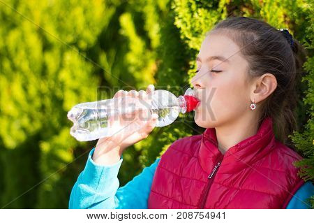 Beautiful girl is drinking water the hot sun in the park. Healthily concept. Healthy lifestyle concept. copy space. Portrait happy smiles beautiful girl . Portrait smiles girl. girl drinking water
