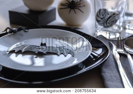 Elegant Halloween table settings in black white colors. Halloween party typical symbols bat and spiders.