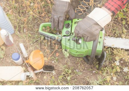 Lumberjack fixing / maintaing the chainsaw outdoors.