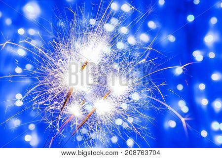 Three Bengal fire sparkles in New year and Christmas on blurred blue background