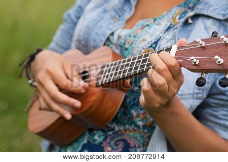 Closeup photo of young woman playing on Ukulel.