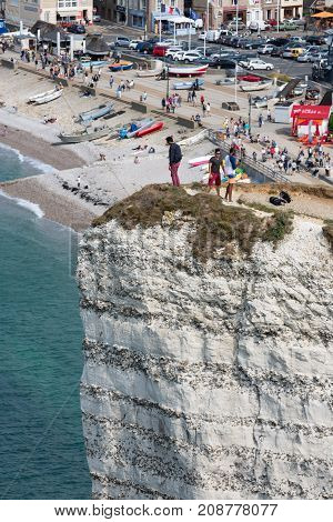 ETRETAT, FRANCE - AUGUST 25, 2017: Aerial view of tourists standing at a high cliff near the beach and promenade of Etretat in Normandy, France