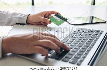 Business woman holding credit card entering security code and using laptop computer and digital tablet online shopping concept.