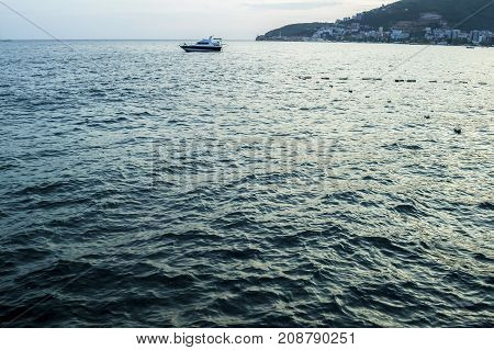 View of the Adriatic Sea and the silhouette of the old town of Budva in Monteregro. The ship is on the roadstead.