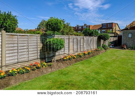 Backgarden tidy flower bed with fence and newly mown grass.