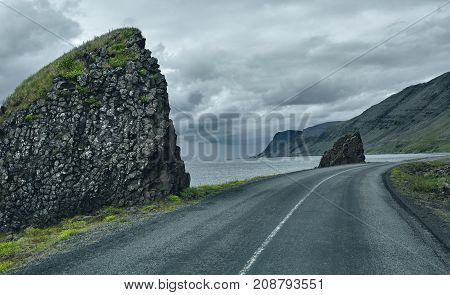 Travel to Iceland. A road along the sea with fog to the town of Isafjordur and a view of the fjord. focus on the road
