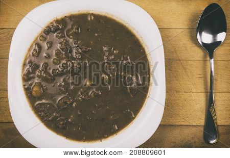 Photo from above of stew with spoon on wooden table background. A plate full of stew (goulash. Ttraditional humgariam goulash with potatoes on wooden background with vignette.