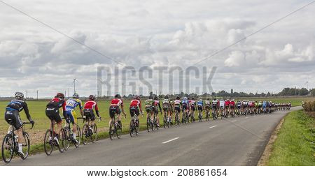 Le Gault-Saint-Denis France - October 08 2017: The peloton riding on a road in the plain with windmills in a cloudy day during the Paris-Tours road-cycling race.