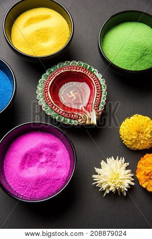 Stock Photo of happy diwali greeting card clicked using elements of Diwali festival like colourful rangoli in bowls, diwali clay lamp or diya and flowers