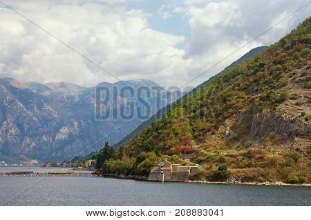 Picturesque autumn of Montenegro. View of the mountain with Church of Our Lady of the Angels on the coast of the Bay of Kotor (Adriatic Sea) near Stoliv village and fishing farm