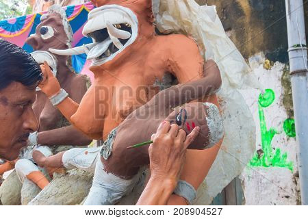 KUMARTULI KOLKATA INDIA - OCTOBER 10 2014 - Artist preparing clay idols of female demons to be used during Kali Puja worshipping of Goddess Kali Hindu festival of Deepavali or Diwali.