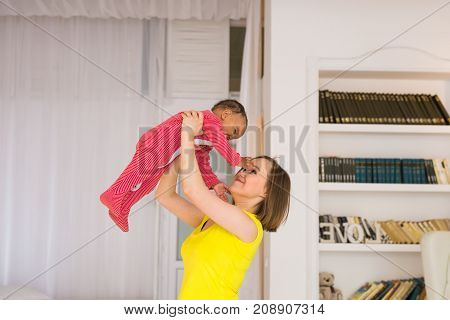 happy family. Mother throws up baby, playing at home.