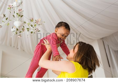 happy family. Mother throws up baby, playing at home.