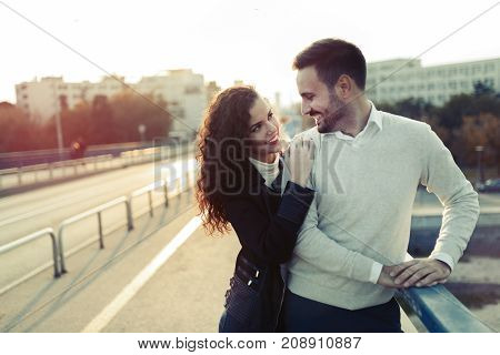 Happy couple cuddling while enjoying time spent together on bridge