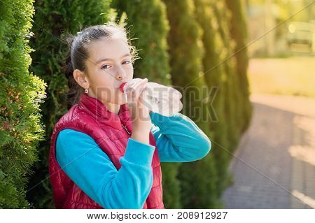 Beautiful girl is drinking water the hot sun in the park. Healthily concept. Healthy lifestyle concept. copy space. Portrait happy smiles beautiful girl . Portrait smiles girl. girl drinking water