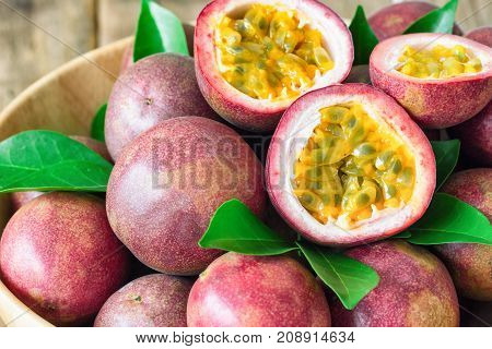 Close up fresh passion fruit in wood bowl on wood table in side view with copy space for background or wallpaper. Ripe passion fruit so delicious sweet and sour. Tropical fruit. Macro concept. Sliced passion fruit selective focus.