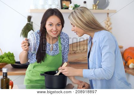 Two young happy woman making cooking in the kitchen. Friendship and culinary concept.
