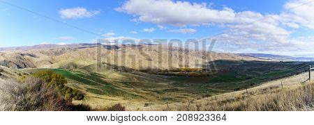 Panoramic image of Lindis Pass Scenic Reserve is the highest point on the South Island's state highway network of New Zealand offering mountain and tussock grassland scenery in Autumn
