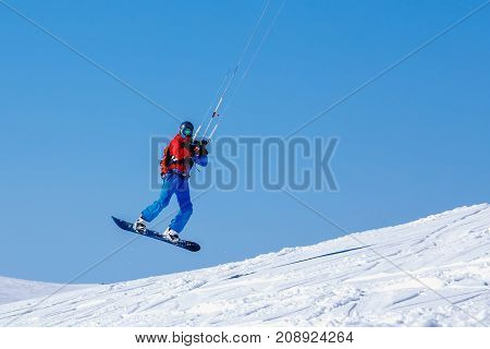 Snowboarder with a kite on fresh snow in the winter in the tundra of Russia against a clear blue sky. Teriberka, Kola Peninsula, Russia. Concept of winter sports snowkite.