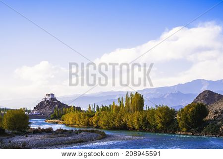 Stakna Gompa and Indus river before sunset with cloudy sky and mountains background