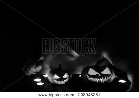 A Guy Disguised As A Maniac Is Sitting With A Knife, And There Are Two Pumpkins On The Table. Hallow
