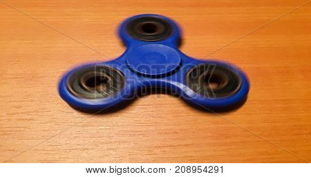 Spinner isolated on wood background. Blue toy spinner. Hand spinner isolated on wooden background. Toy spiner spinner