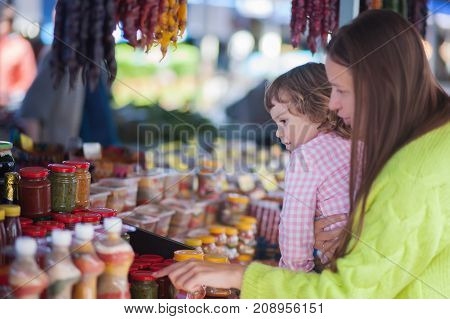 Young woman and her daughter at the bazaar buying food ingridients.