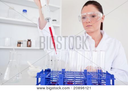 Hezká žena biolog drží manuální pipety s vzorek ze zkumavky