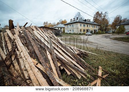 Typical russian autumn landscape with firewood near ragged houses. Russian village,