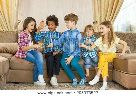 Kids playing rock paper scissors. Group of children indoor. Family competition games.