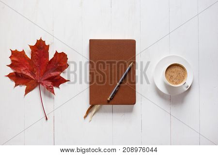 The concept of autumn mood. Morning coffee, diary and colored maple leaves. Top view.