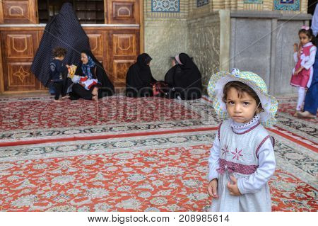 Fars Province Shiraz Iran - 19 april 2017: Shah Cheragh Shrine Portrait of an unknown little girl about four years old standing in the courtyard of the mosque on the background of pilgrims.