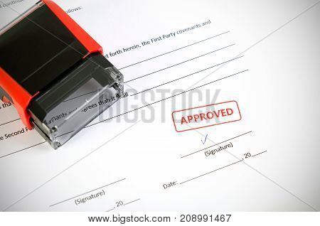 Automatic stamp on the contract document. Approved agreement. approve permit paperwork document automatic stamp authority agreement concept