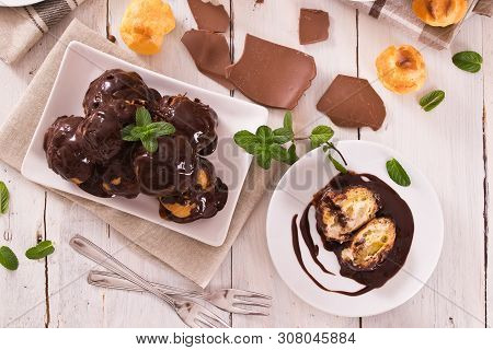 Chocolate Profiteroles With Whipped Cream On White Dish.