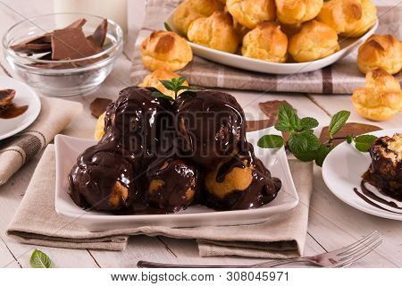 Chocolate Profiteroles With Whipped Cream On White Dish.