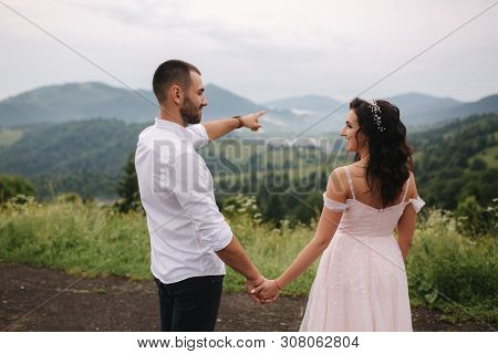 Beautiful Young Wedding Couple Standing On The Green Slope, Hill. Groom And Bride In Carpathian Moun