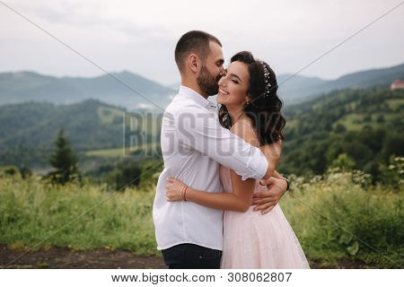 Beautiful Young Wedding Couple Standing On The Green Slope, Hill. Groom And Bride In Carpathian Moun
