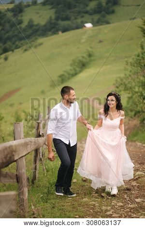 Beautiful Young Wedding Couple Standing On The Green Slope, Hill. Groom And Bride In Carpathian Moun