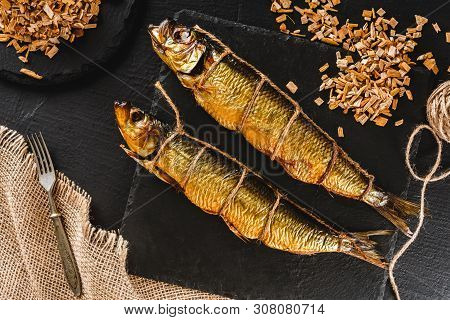 Appetizing Smoked Fishes With Sawdust And Burlap Texture On Slate Stone Background. Mediterranean Fo