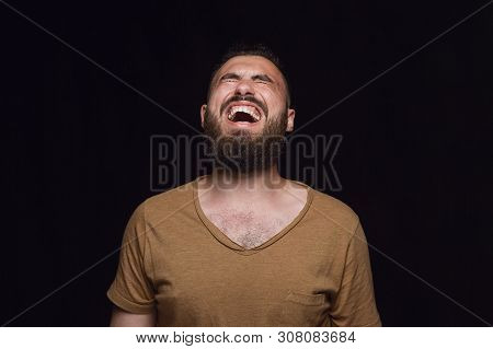 Close Up Portrait Of Young Man Isolated On Black Studio Background. Photoshot Of Real Emotions Of Ma