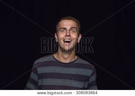 Close Up Portrait Of Young Man Isolated On Black Studio Background. Photoshot Of Real Emotions Of Ma