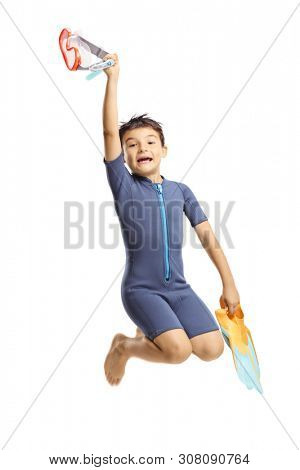 Full length portrait of a happy boy in a wetsuit holding swmming fins and jumping isolated on white background