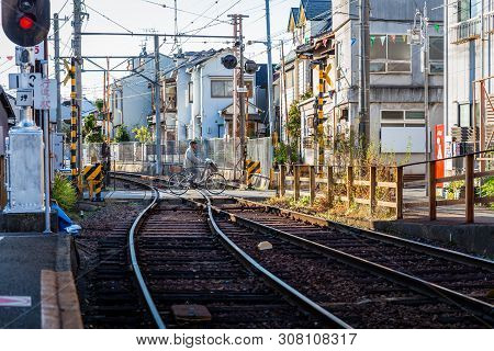 Kyoto, Japan - November 20, 2018: Japanese Man Riding Bike To Cross Railroad Tracks Of Keifuku Elect