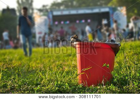 Red Litter On Green Grass. Garbage In The Nature After The Concert.