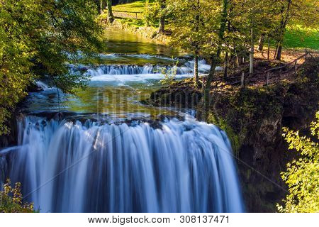 Magnificent cascade of waterfalls on the Korana River. The forest surround the city and the river. The small Croatian town of Slunj. The concept of ecological, active and photo tourism