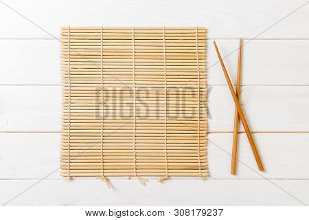 Two Sushi Chopsticks With Empty Bamboo Mat Or Wood Plate On Wooden Background Top View With Copy Sta