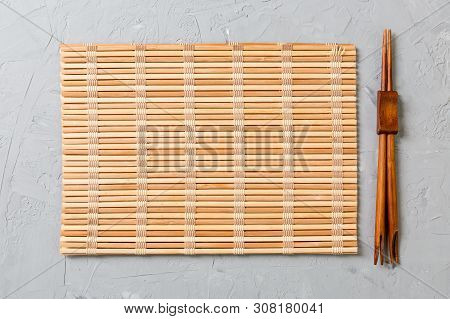 Two Sushi Chopsticks With Empty Bamboo Mat Or Wood Plate On Stone Background Top View With Copy Stac