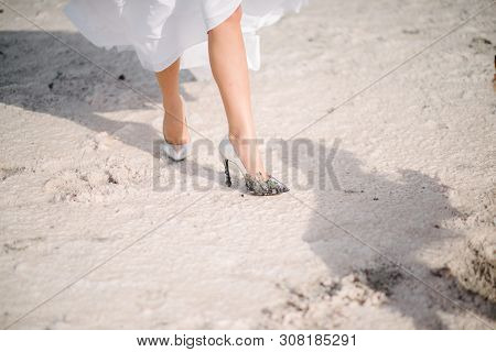 The Legs Of The Bride In A Wedding Dress In Shoes Close Op