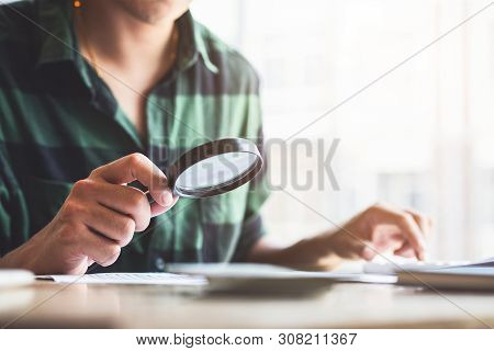 Businessman Looking Through A Magnifying Glass To Documents. Business Assessment And Audit. Magnifyi
